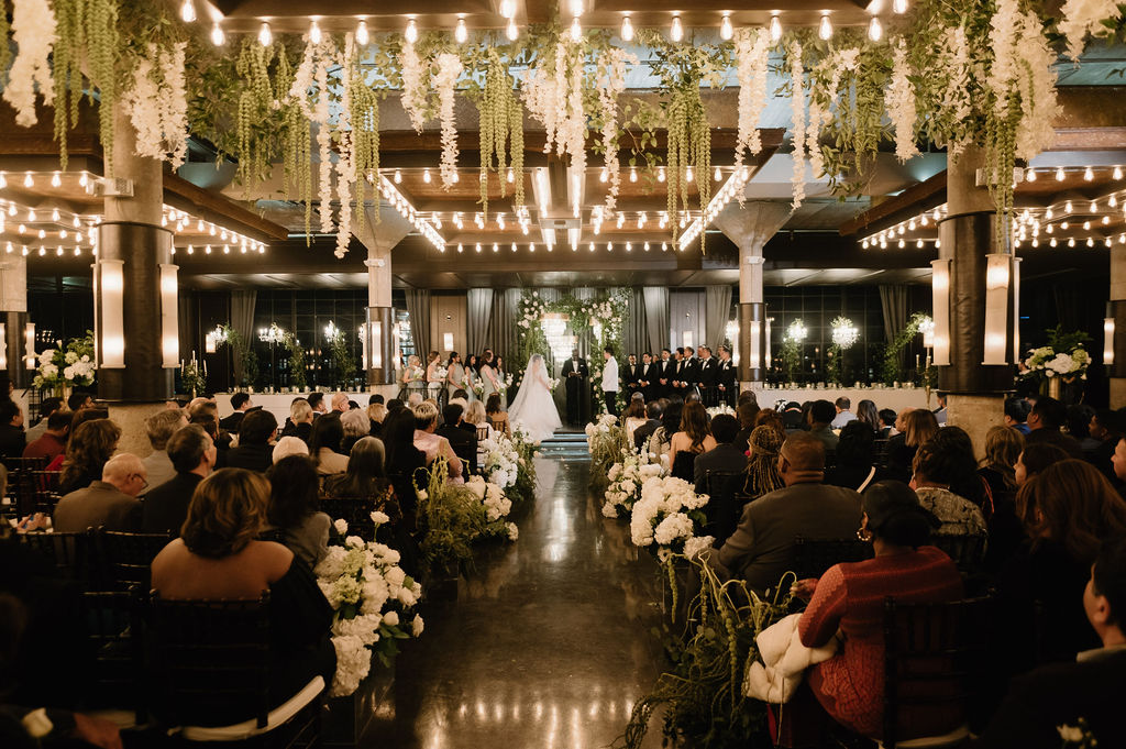 The Astorian wedding ceremony in Houston with floral ceiling installations and guests seated