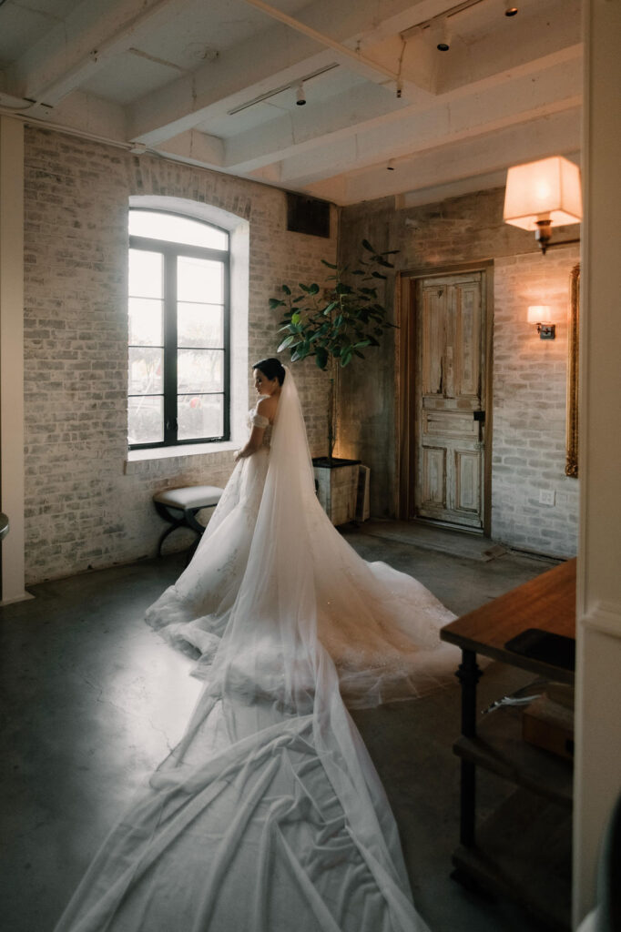Bride in the getting-ready suite at The Astorian Houston with natural light and exposed brick walls